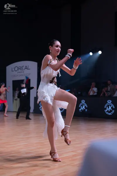 Dancesport competitor: Female dancer: white Latin dance dress with fringe and bronze-colored embellishm