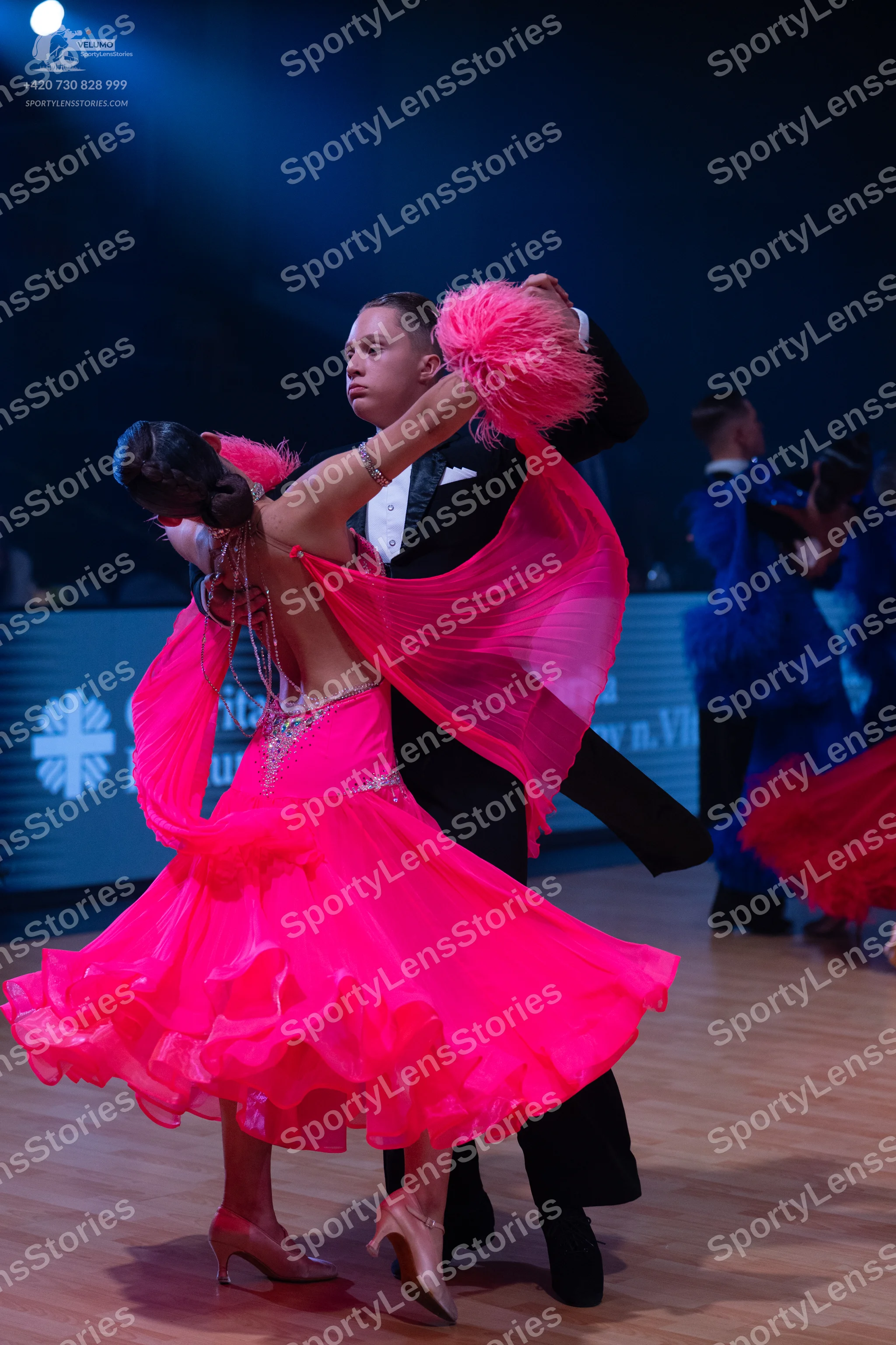 Dancesport competitor: Female dancer: bright pink ballgown with a sparkly bodice, a large layered ruffl