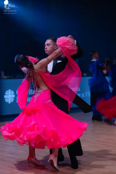 Dancesport competitor: Female dancer: bright pink ballgown with a sparkly bodice, a large layered ruffl