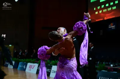 Dancesport competitor: Female dancer: purple latin dress with sequins and large, voluminous, flowing fa