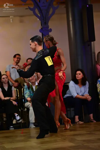 Dancesport competitor: Male dancer: black long-sleeved dance shirt with a dark panel on the shoulder an