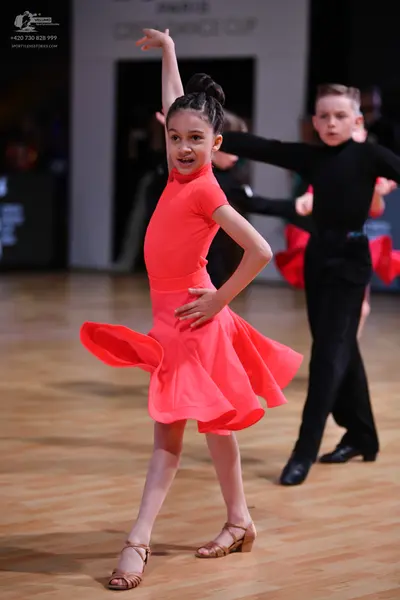 Dancesport competitor: Female dancer: coral-colored latin dress with a flared skirt and high neckline
