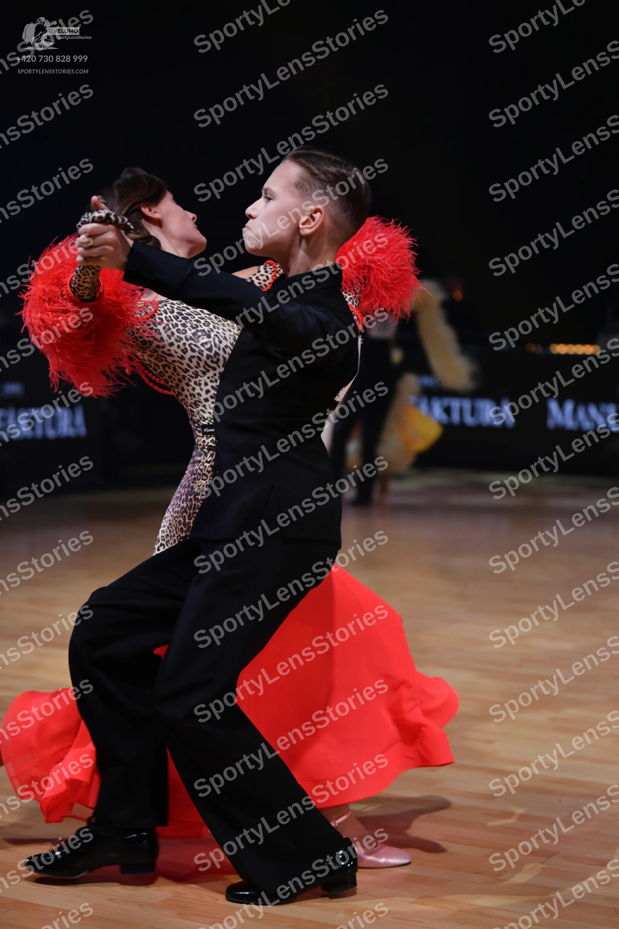 Dancesport competitor: Male dancer: black suit with red feather details on the shoulders