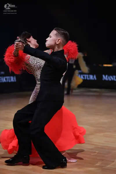 Dancesport competitor: Male dancer: black suit with red feather details on the shoulders