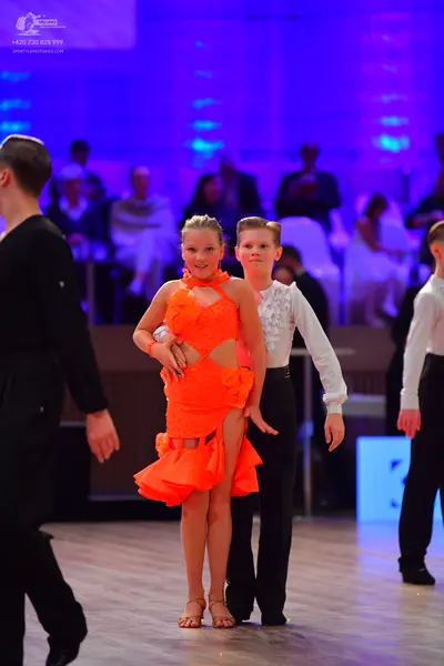 Dancesport competitor: Female dancer: orange Latin dress with ruffles and cutouts