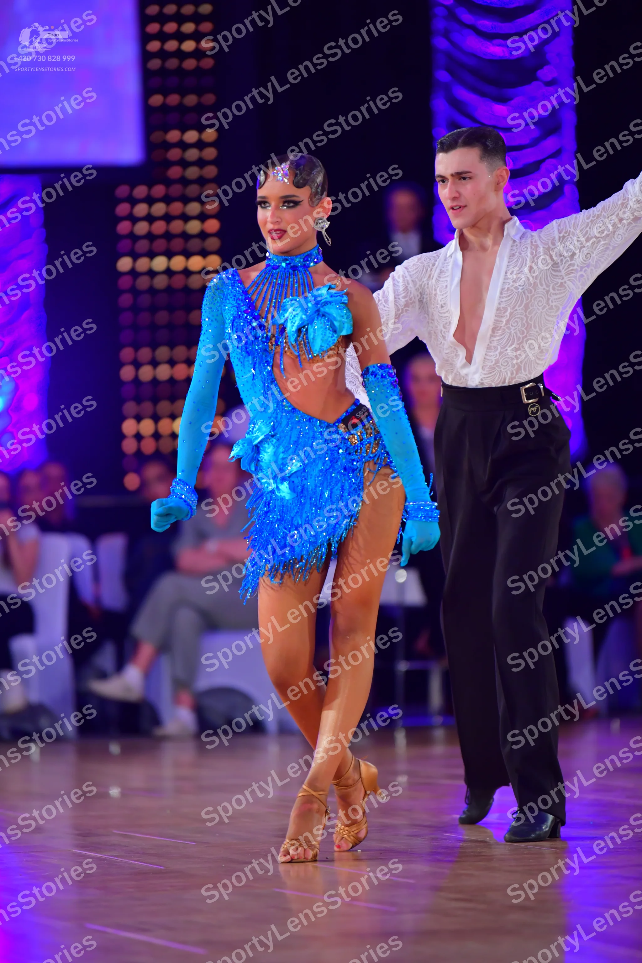 Dancesport competitor: Female dancer: bright blue Latin dance costume with long sleeves/gloves, a high 