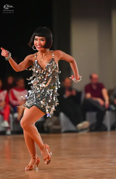 Dancesport competitor: Female dancer: short black latin dress decorated with large silver sequins or pa