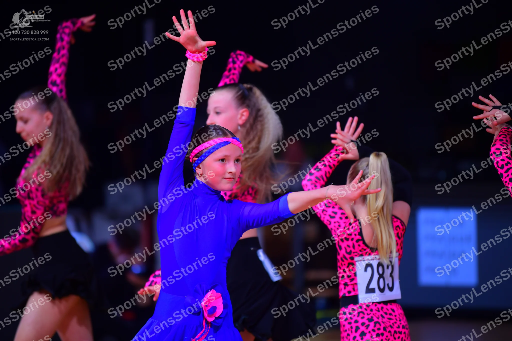 Dancesport competitor: Female dancer: blue long-sleeved latin dress with a pink floral accessory at the