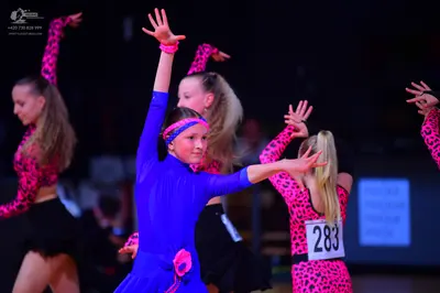 Dancesport competitor: Female dancer: blue long-sleeved latin dress with a pink floral accessory at the