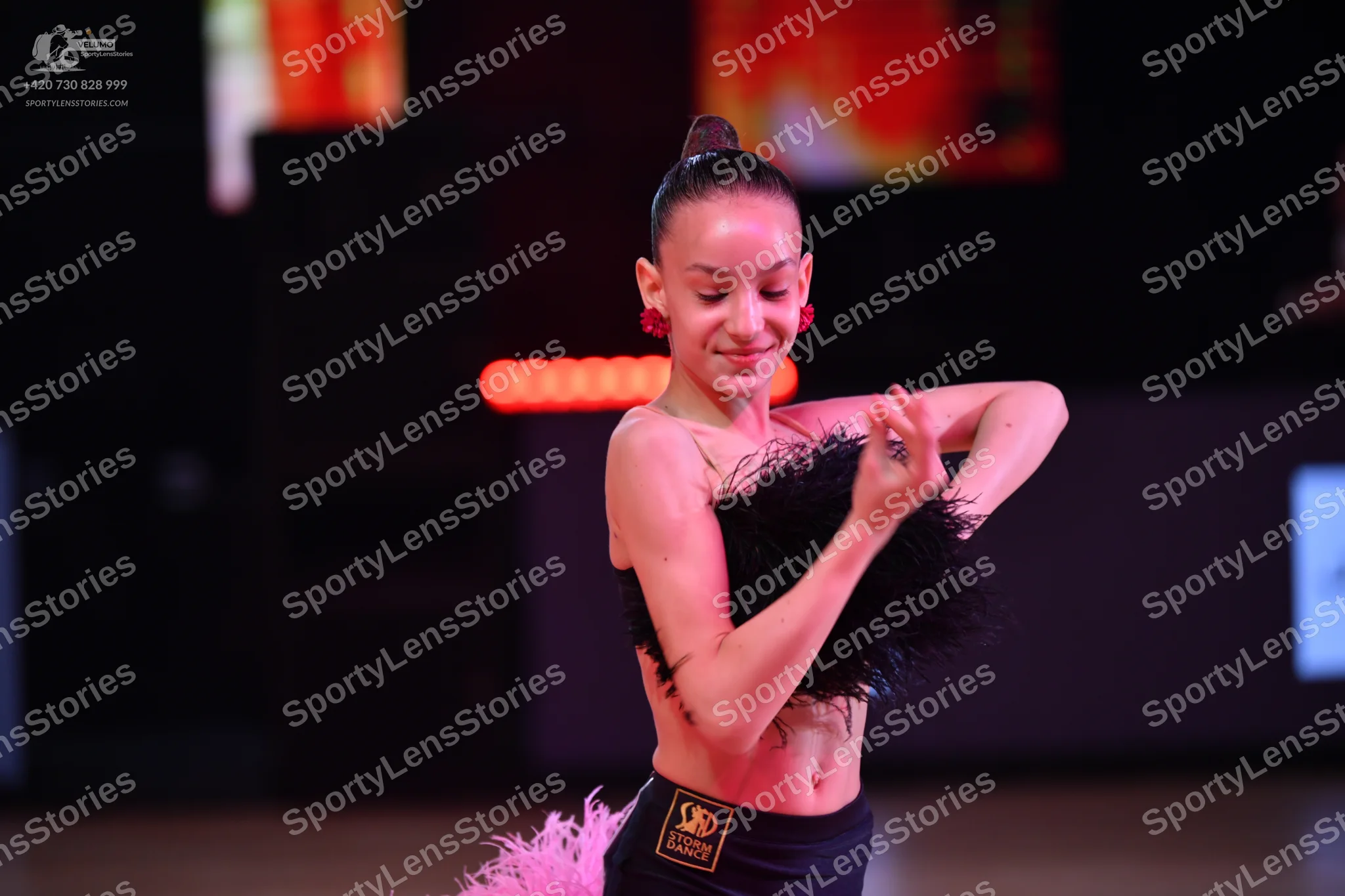 Dancesport competitor: Female dancer: black Latin dance costume with black feathers on the top and pink
