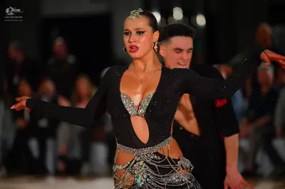Dancesport competitor: Female dancer: black long-sleeved Latin costume with a deep V-neck, midriff cuto