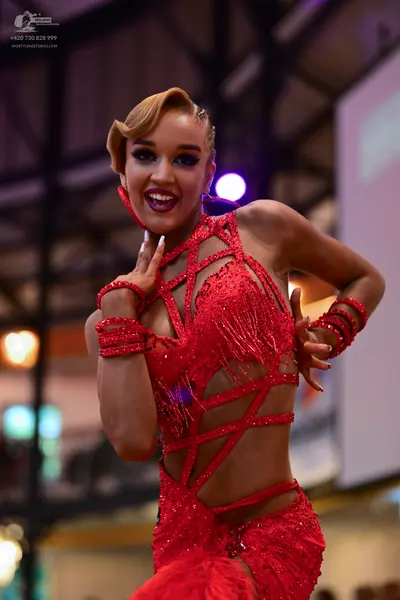 Dancesport competitor: Female dancer: red latin dress with sequin embellishments, cutouts, and fringes,