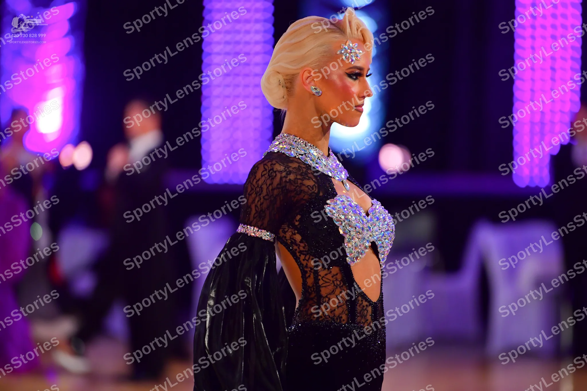 Dancesport competitor: Female dancer (foreground): black latin dress with lace, sequins, and large puff