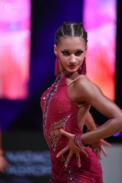 Dancesport competitor: Female dancer: dark magenta Latin dress with crystal embellishments and side cut