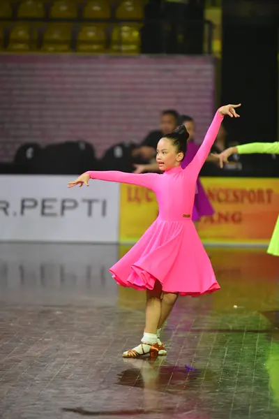 Dancesport competitor: Female dancer: bright pink long-sleeved latin dress