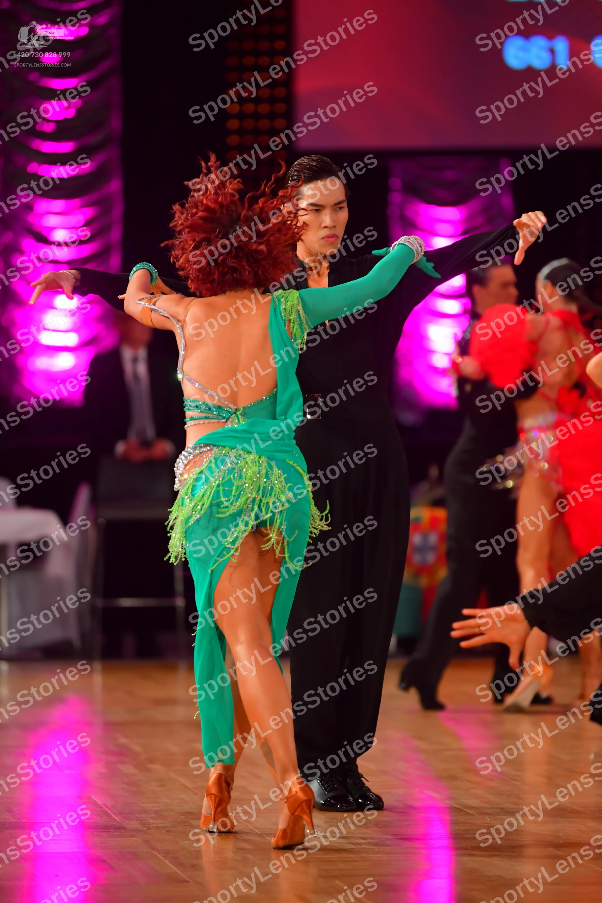 Dancesport competitor: Female dancer: green Latin dress with long sleeves, fringe, and sequins