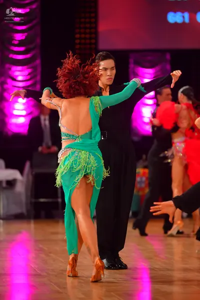 Dancesport competitor: Female dancer: green Latin dress with long sleeves, fringe, and sequins