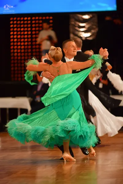 Dancesport competitor: Female dancer: green latin dress with voluminous green feather-like fringe on th