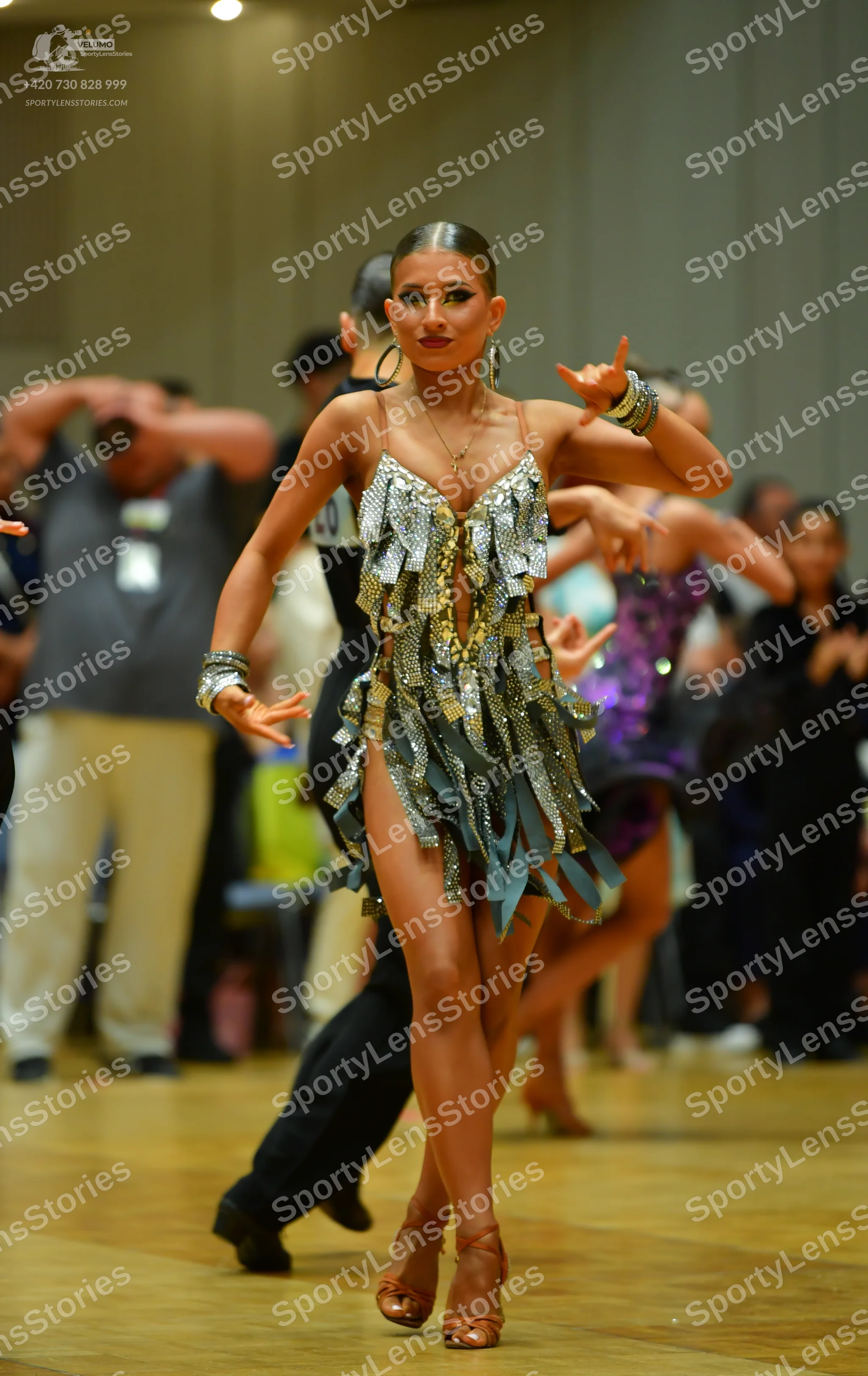 Dancesport competitor: Main female dancer: silver and gold sequined Latin dress with light blue fringe