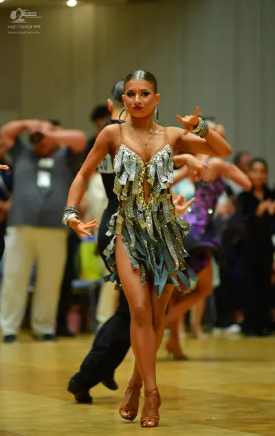 Dancesport competitor: Main female dancer: silver and gold sequined Latin dress with light blue fringe 