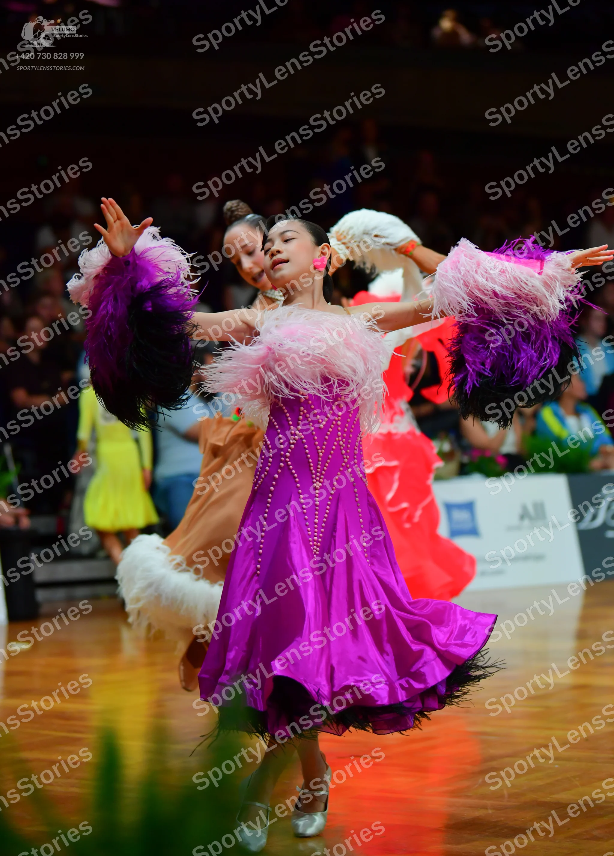 Dancesport competitor: Main female dancer: magenta satin-like Latin dress with vertical lines of small