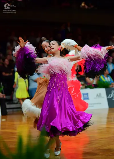 Dancesport competitor: Main female dancer: magenta satin-like Latin dress with vertical lines of small 