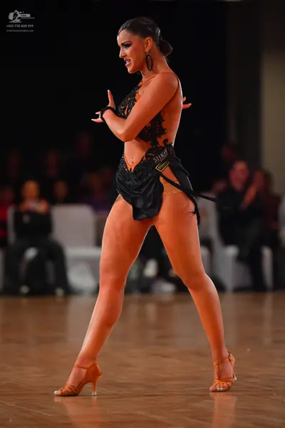 Dancesport competitor: Female dancer: black Latin dress with lace and mesh detailing, paired with large
