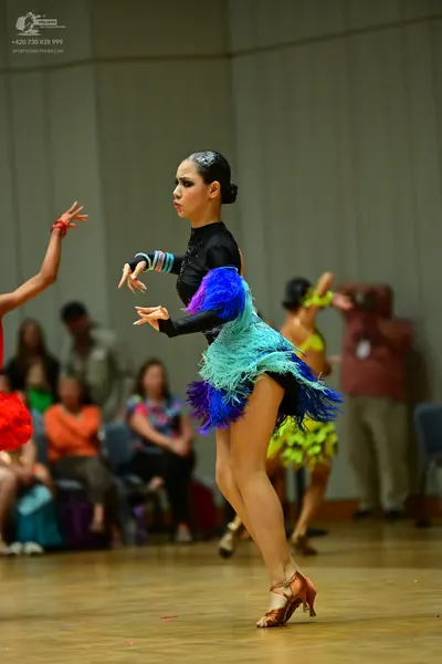 Dancesport competitor: Female dancer in foreground: black long-sleeved Latin dance dress with voluminou