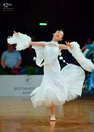 Dancesport competitor: Female dancer: white ballgown made of lace and mesh, featuring voluminous ruffle