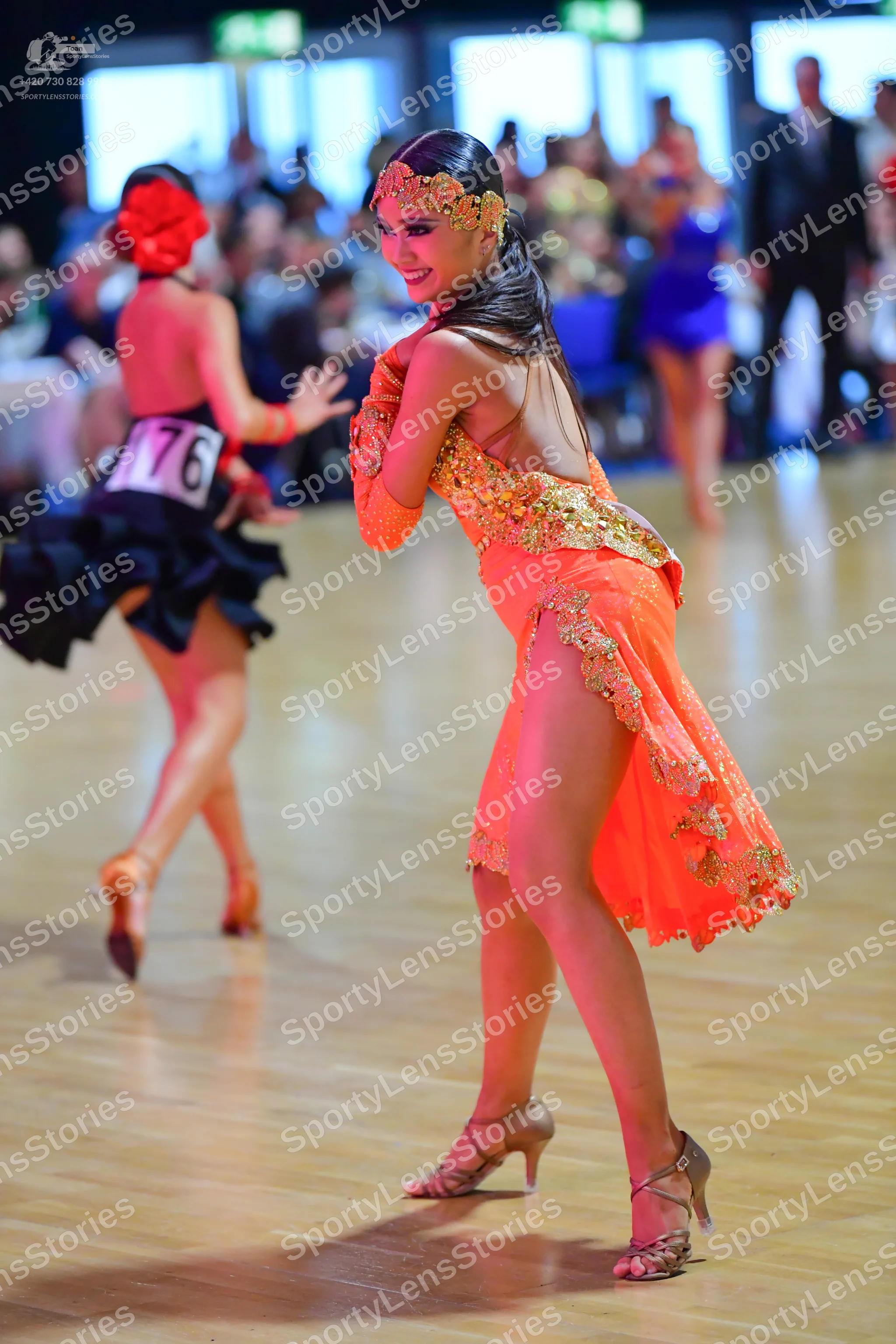 Dancesport competitor #76: Female dancer in foreground: orange latin dress with gold sequins and lace, long