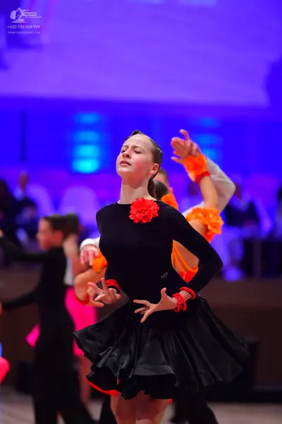 Dancesport competitor: Main female dancer: black long-sleeved latin dress with a red fabric flower at t