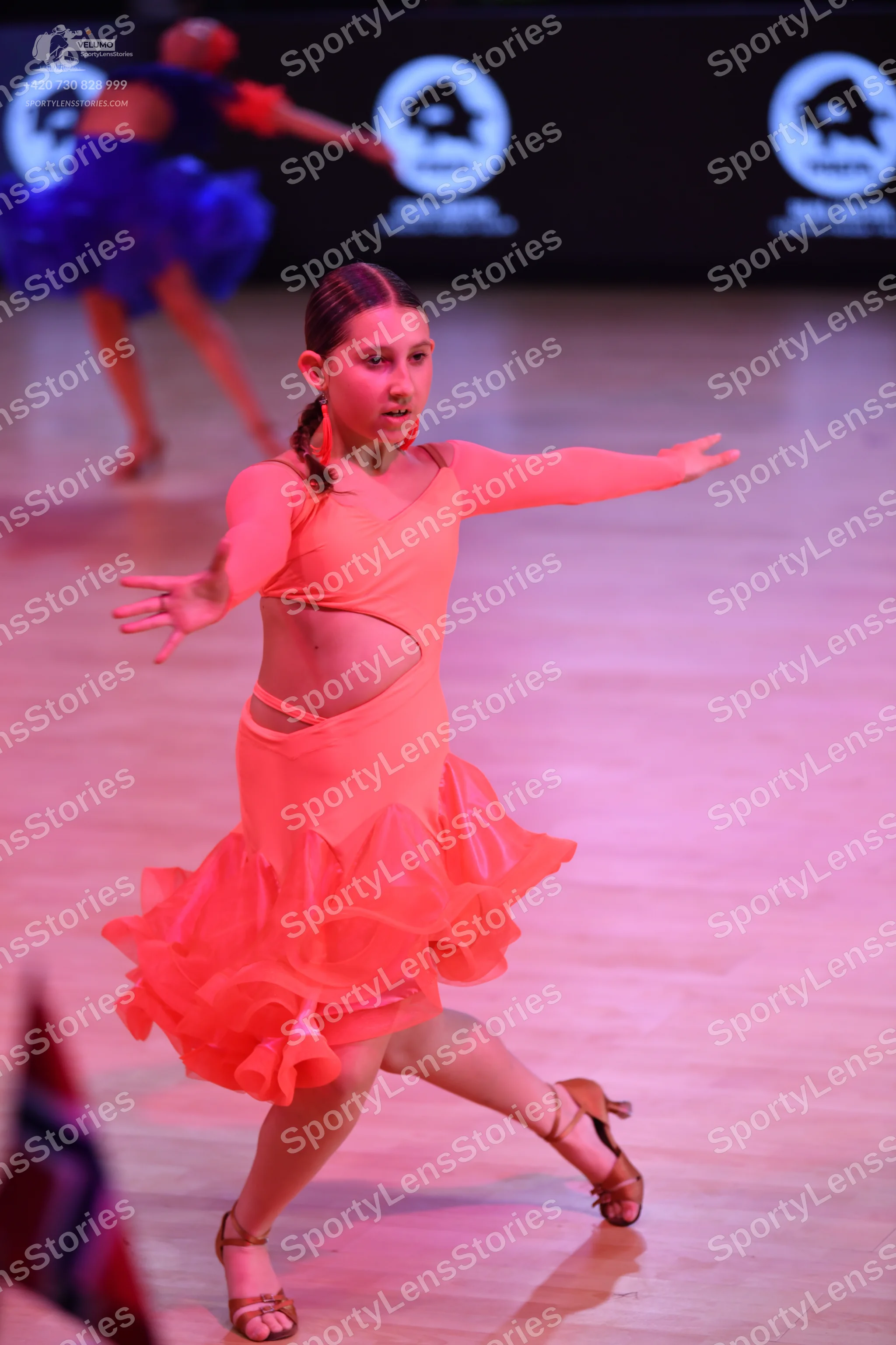 Dancesport competitor: Female dancer in foreground: peach-colored long-sleeved latin dress with side cu