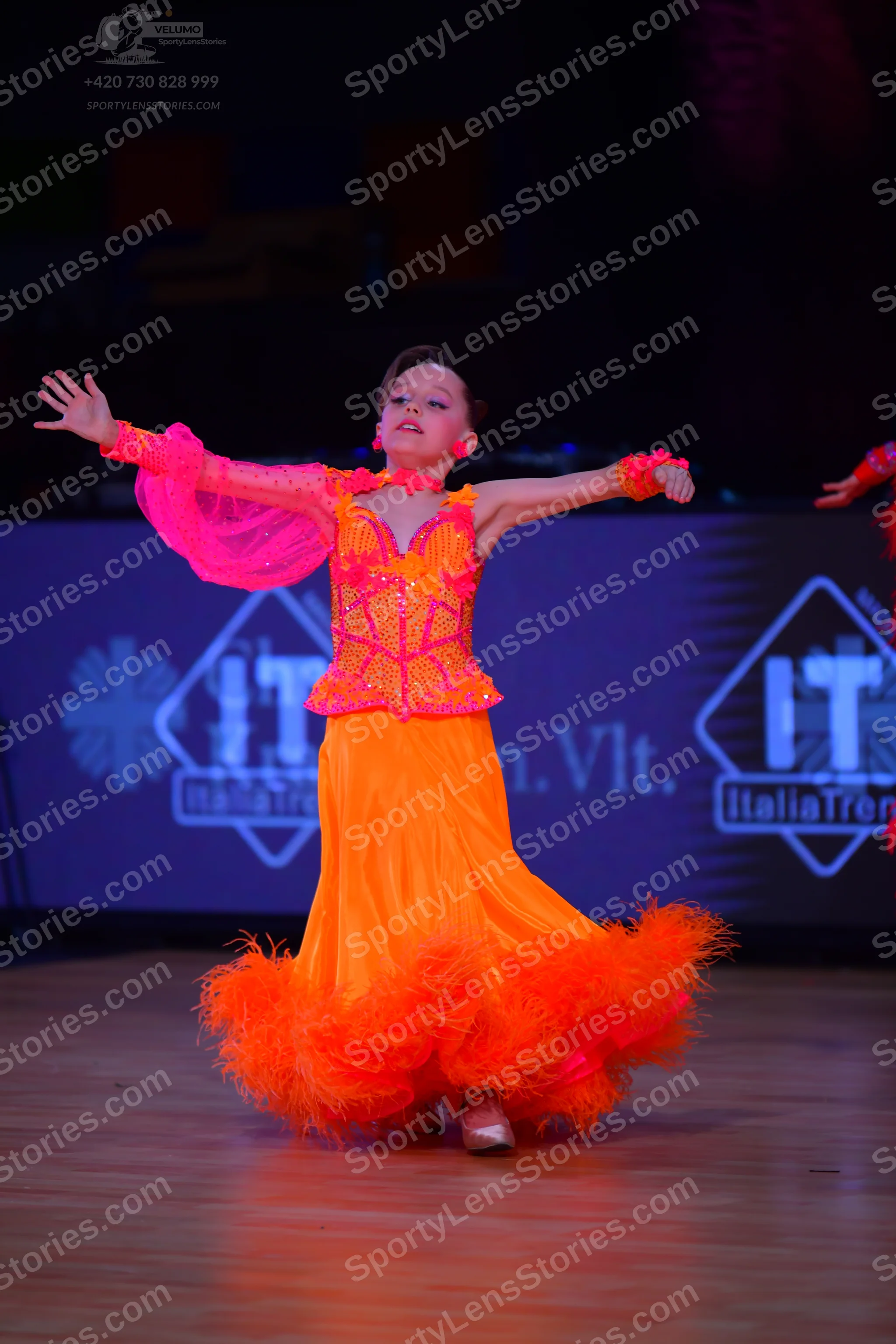 Dancesport competitor: Female dancer: bright orange and pink Latin dance dress with a sequined bodice, 