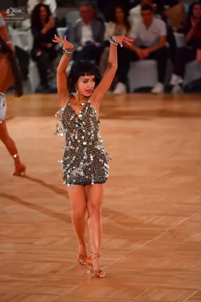 Dancesport competitor: Female dancer: black latin dress decorated with large silver sequins, and silver