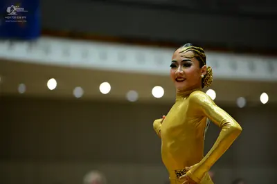 Dancesport competitor #128: Female dancer: gold, long-sleeved, high-neck bodysuit in a shiny, metallic fabri