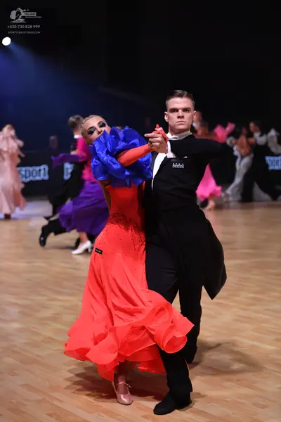 Dancesport competitor: Main female dancer: red ballroom gown with large blue ruffled sleeves and a volu