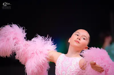 Dancesport competitor: Female dancer: light pink Latin dress with a sequined bodice and large pink feat