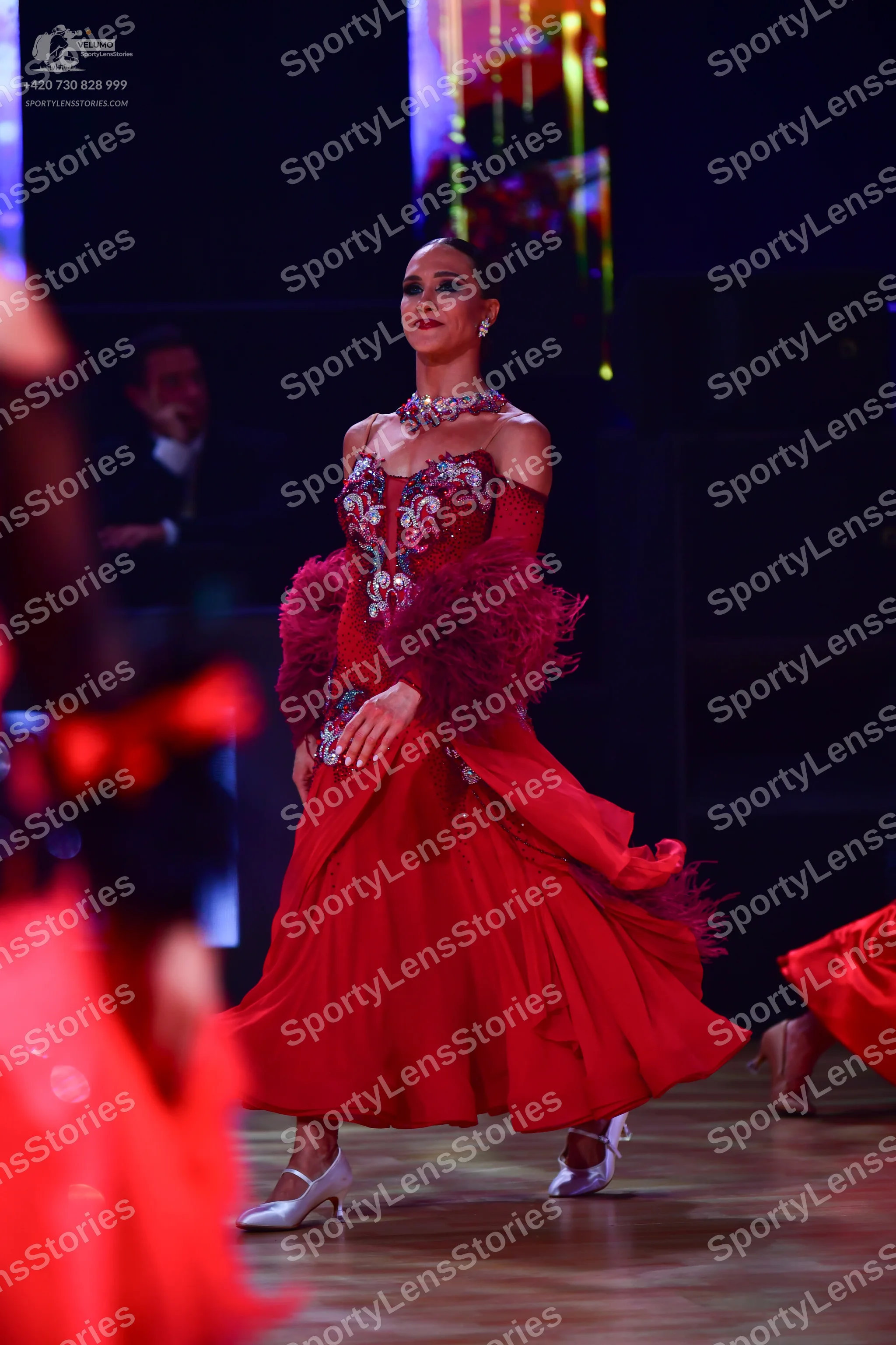 Dancesport competitor: Female dancer: red ballroom dress with a sequined bodice, large red feather acce