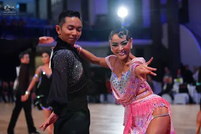 Dancesport competitor: Male dancer in foreground: black long-sleeved shirt with silver sequins on the c