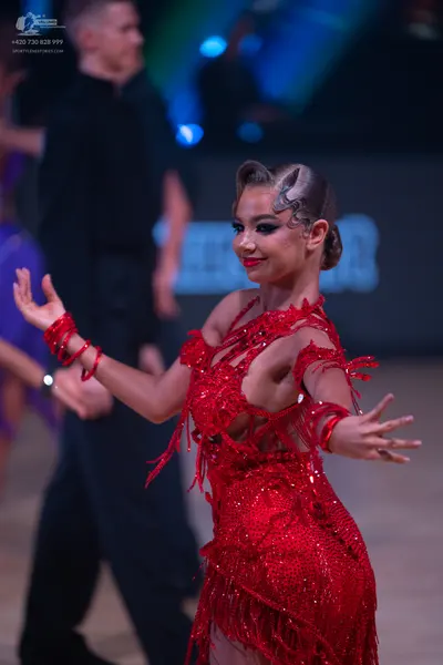 Dancesport competitor: Female dancer: red latin dress with sequins and fringe, with matching red wristb