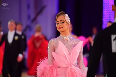 Dancesport competitor: Female dancer in foreground: pink long-sleeved dress with a sequined bodice, a l