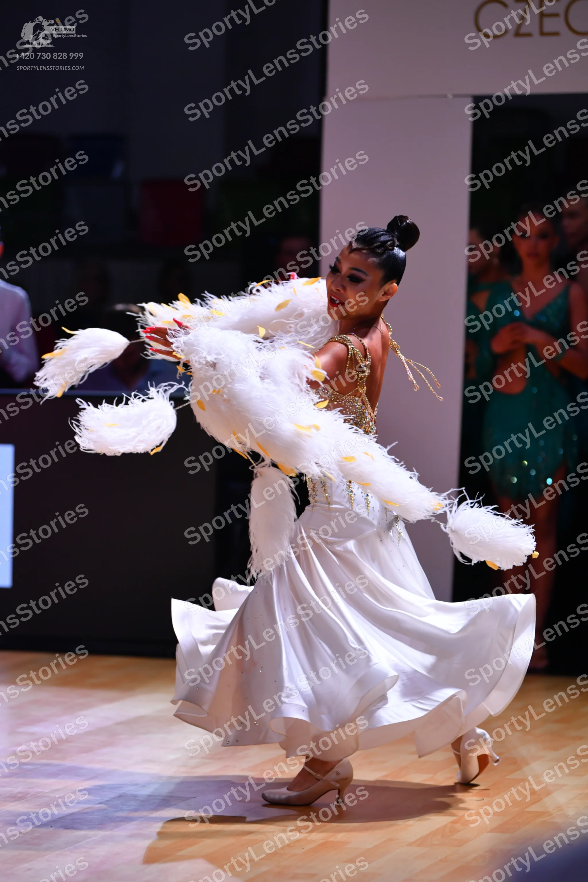 Dancesport competitor: Female dancer in foreground: white and gold ballgown with a sequined/beaded bodi