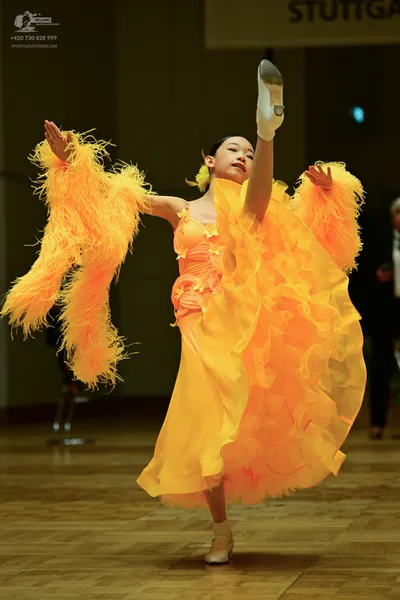 Dancesport competitor: Female (left dancer)**:  Orange, floor-length gown made of a silky fabric