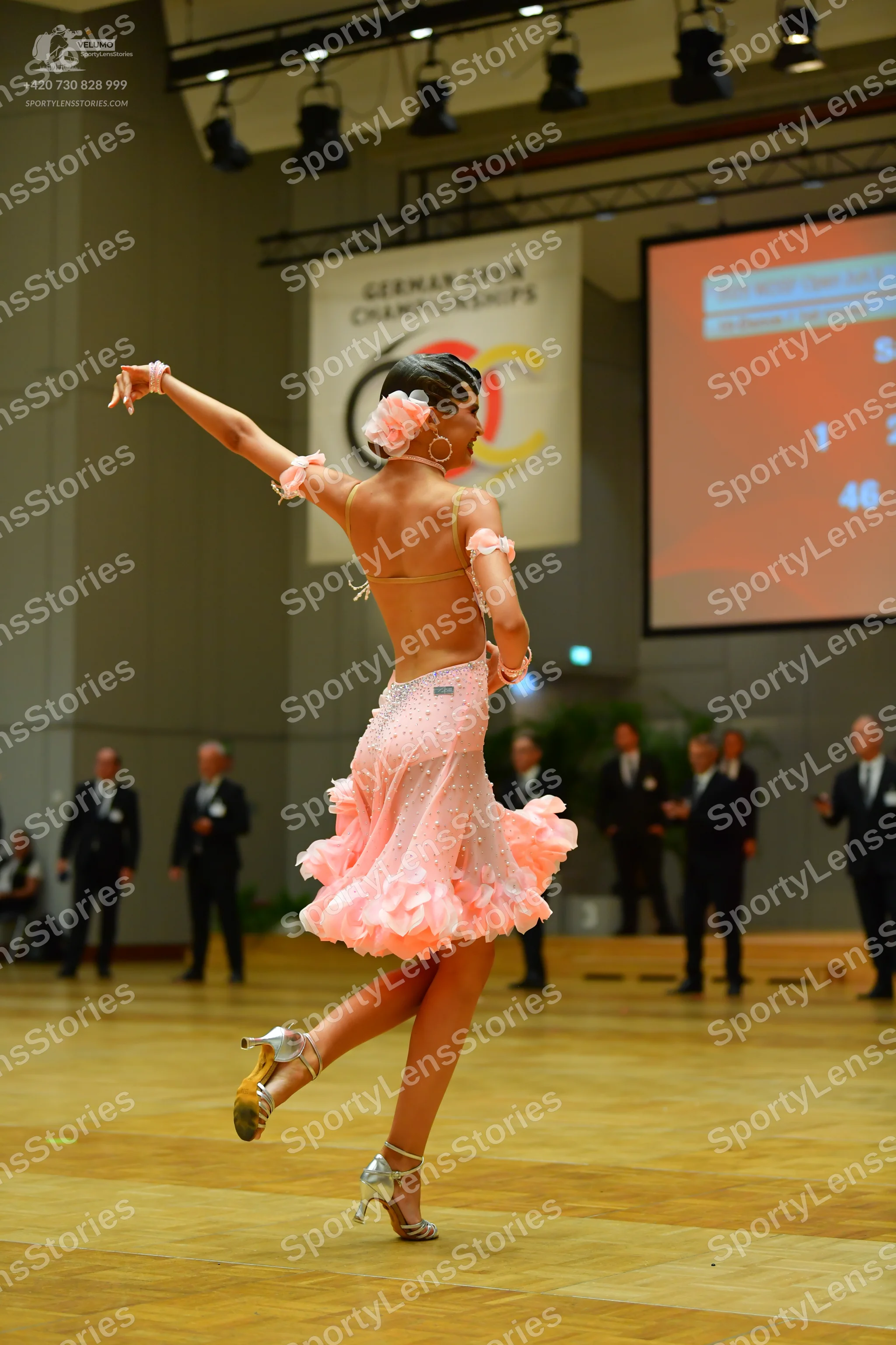 Dancesport competitor: Female dancer: light pink latin dress with a ruffled skirt, thin straps, and sma