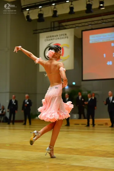Dancesport competitor: Female dancer: light pink latin dress with a ruffled skirt, thin straps, and sma