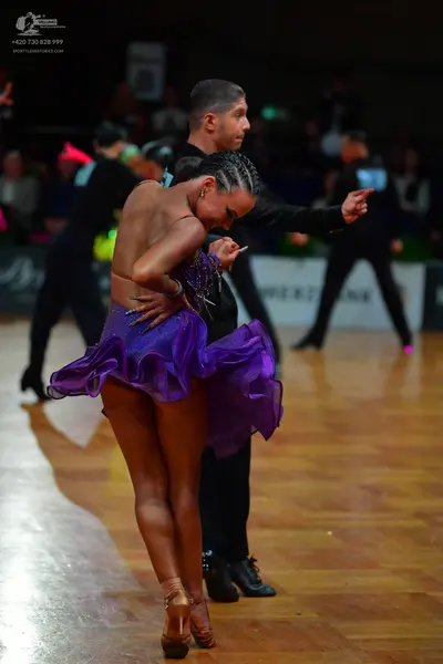 Dancesport competitor: Female dancer: purple latin dress with a ruffled, layered skirt