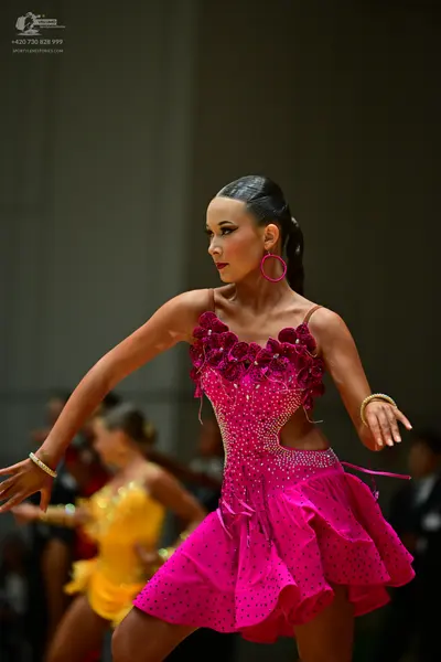Dancesport competitor: Female dancer in foreground: magenta Latin dance dress with sequins, 3D floral a