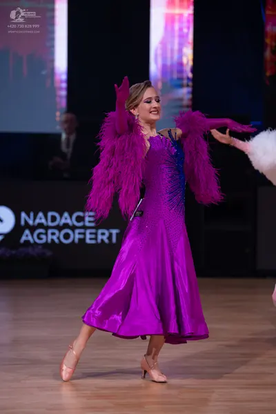 Dancesport competitor: Female dancer: purple satin ballroom dress with large purple feather trim on the