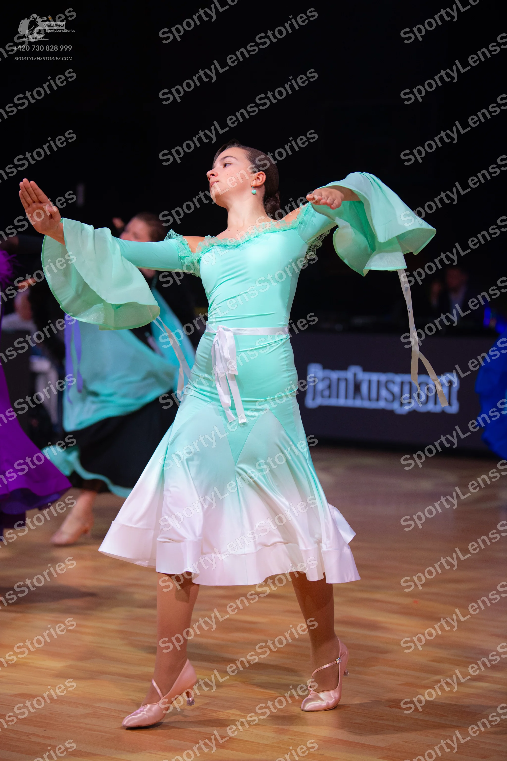 Dancesport competitor: Female dancer: mint green and white ombre latin dress with large, flared bell sl