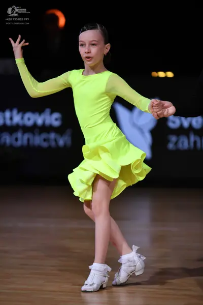 Dancesport competitor: Female dancer: neon yellow long-sleeved Latin dress with a ruffled skirt